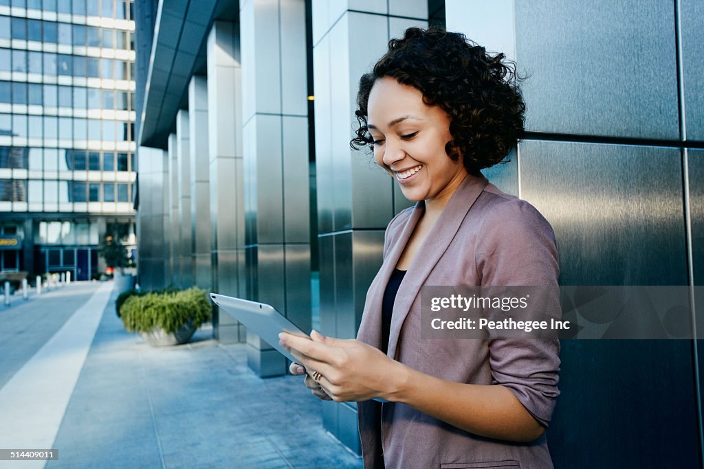 Mixed race businesswoman using tablet computer in city