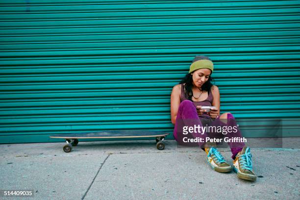 hispanic woman using cell phone on city street - city life authentic stockfoto's en -beelden