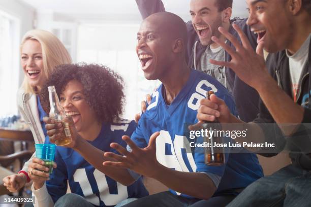 friends drinking beer and cheering at game on television - beer bottle mouth stock pictures, royalty-free photos & images