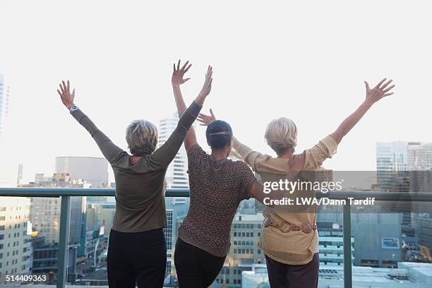 women cheering on urban rooftop - day toronto stockfoto's en -beelden