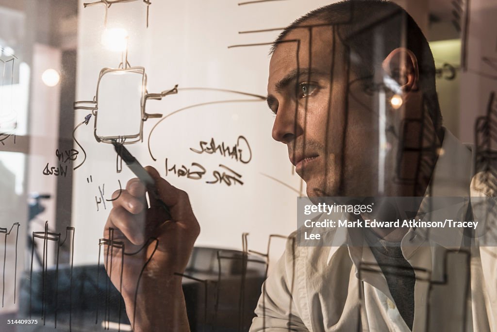 Caucasian businessman writing on glass