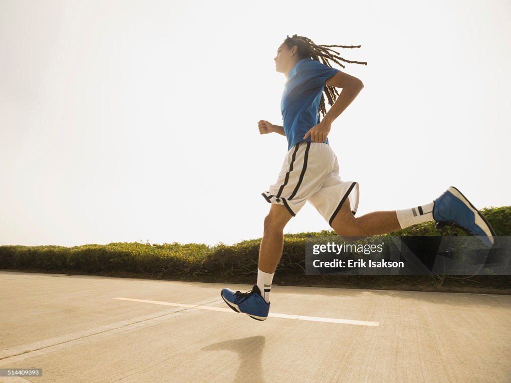 Black teenage boy running on street