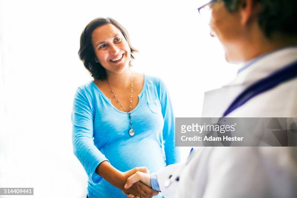 pregnant woman shaking doctorís hand - pregnant women greeting stockfoto's en -beelden