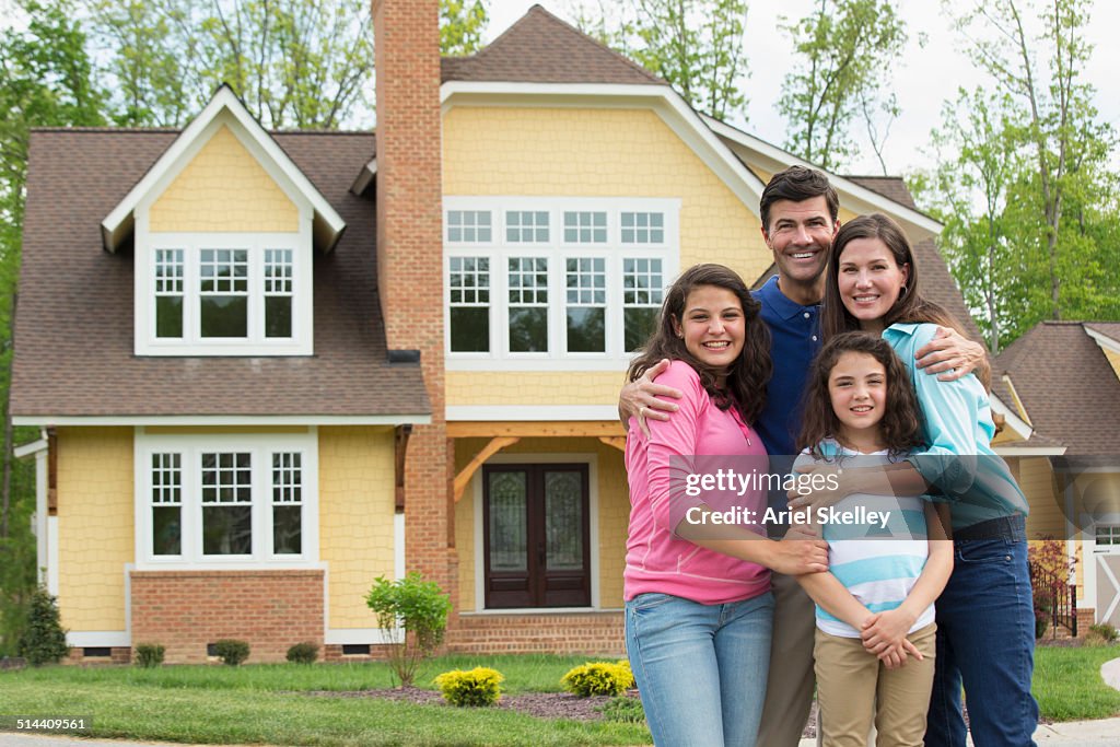 Caucasian family smiling outside house