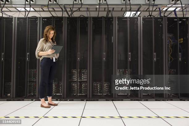businesswoman using tablet computer in server room - network server stock-fotos und bilder