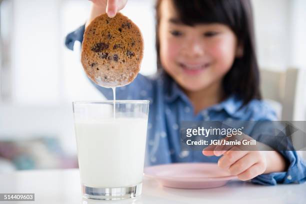 filipino girl dunking cookie in milk - dippen stock-fotos und bilder
