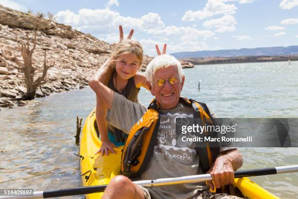 older caucasian man posing in kayak with granddaughter - summer kayaking stockfoto's en -beelden