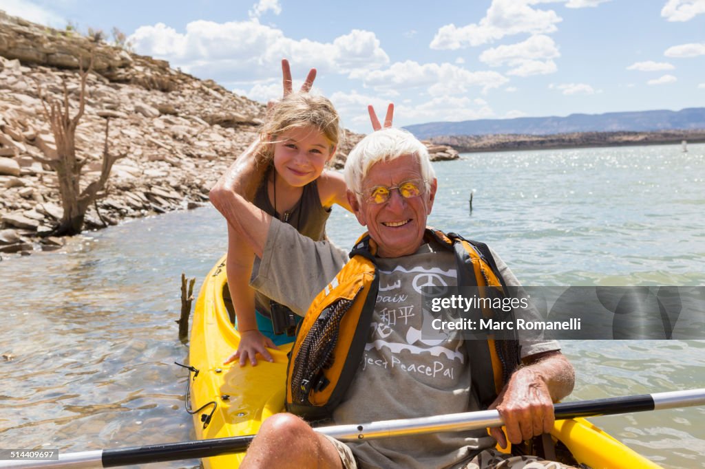 Older Caucasian man posing in kayak with granddaughter