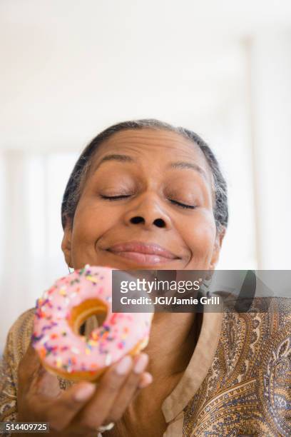 mixed race woman eating donut - eating donuts foto e immagini stock