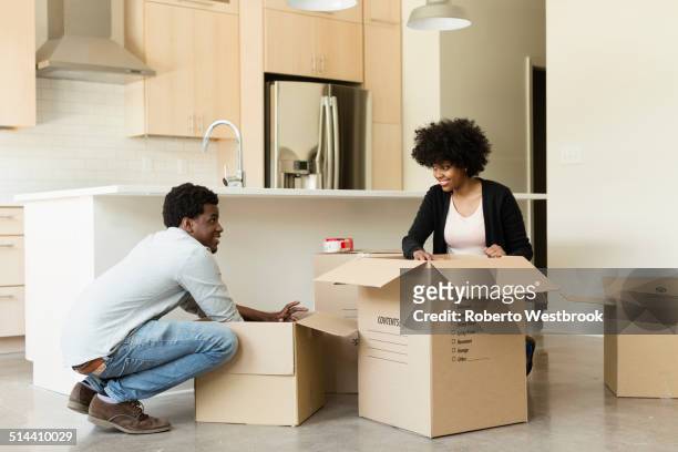 couple unpacking cardboard box in new house - man with moving boxes authentic stockfoto's en -beelden