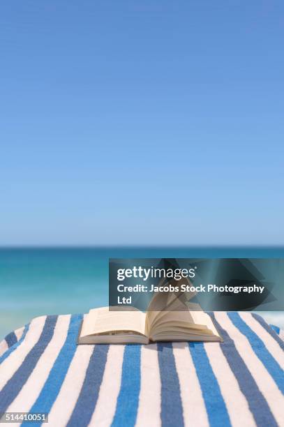 close up of book on deck chair on beach - book blue stock-fotos und bilder