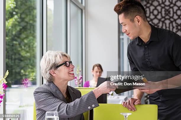 businesswoman paying tab in restaurant - equal pay stockfoto's en -beelden