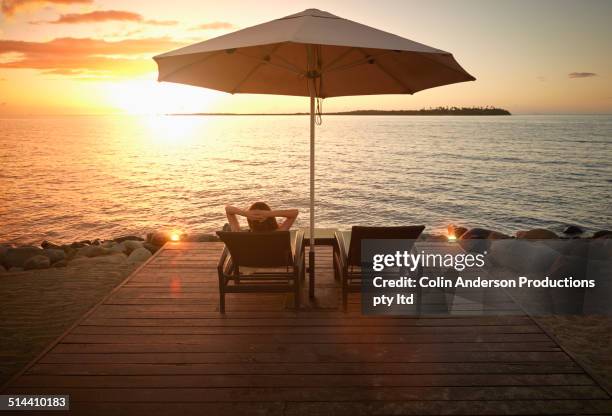 caucasian woman admiring sunset over water, denarau island west, nadi, fiji - デッキチェア ストックフォトと画像