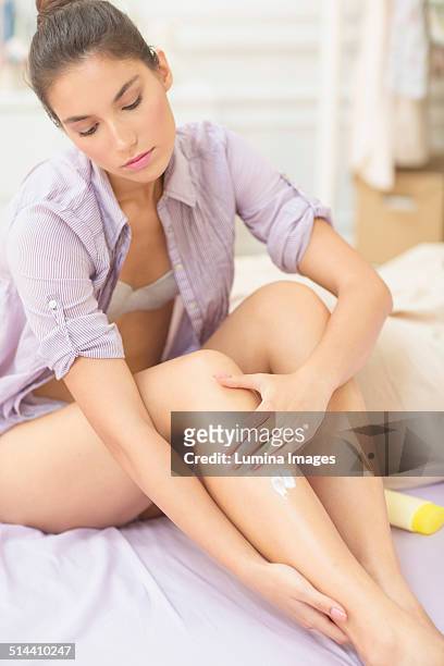 caucasian woman applying moisturizer to leg - woman leg spread stock pictures, royalty-free photos & images