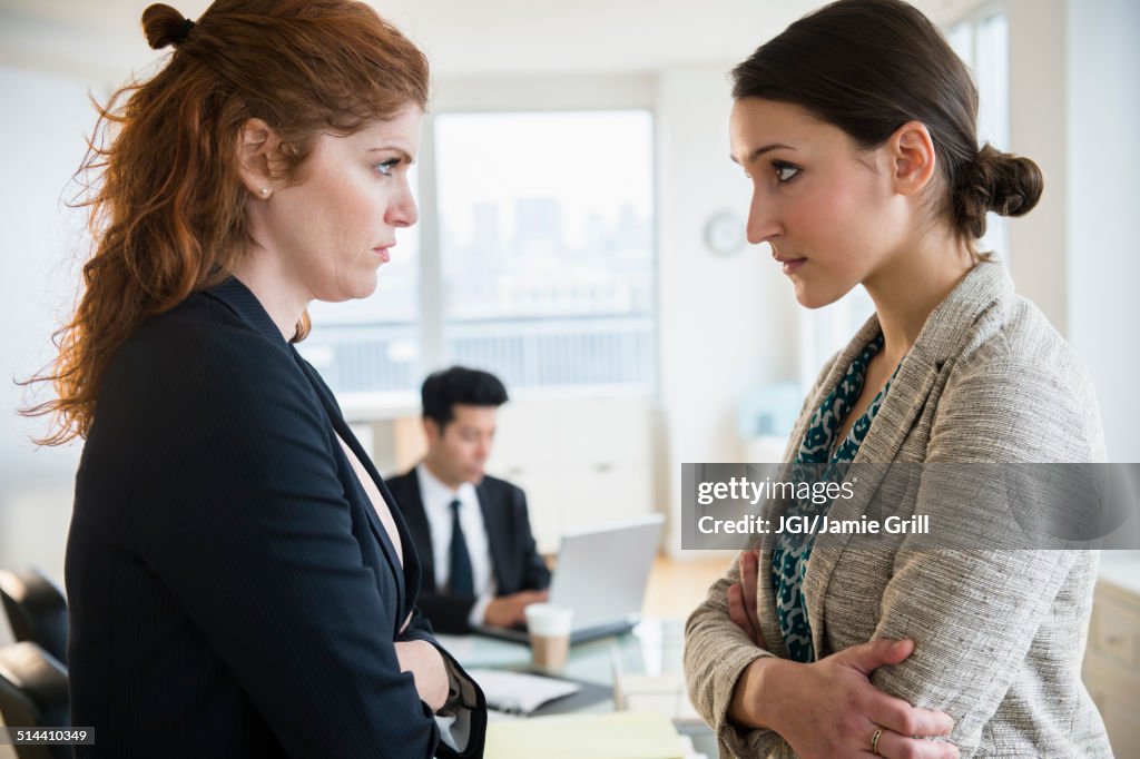 Businesswomen glaring at each other in office