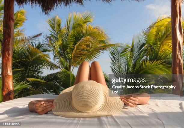 hispanic woman relaxing in hut on beach - beach hut fotografías e imágenes de stock