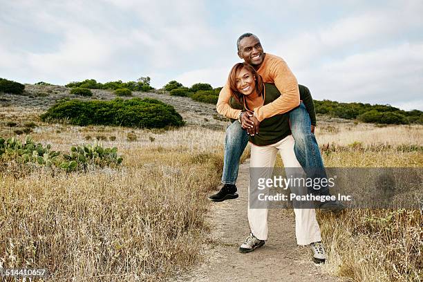 black couple playing on rural path - piggyback stock pictures, royalty-free photos & images