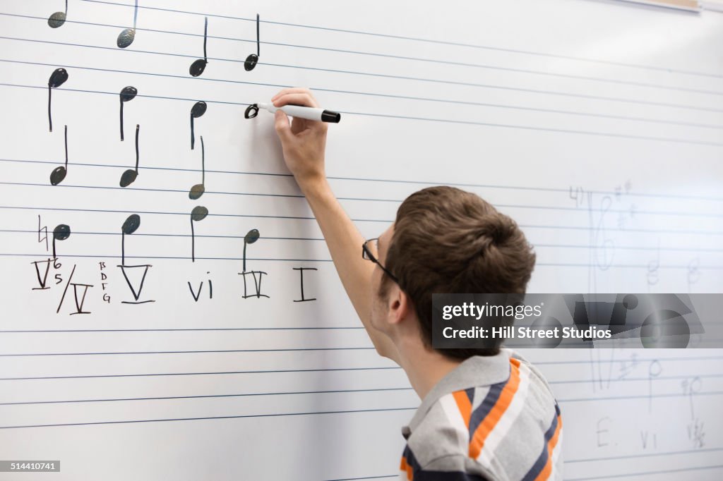 Caucasian student writing on board in music class