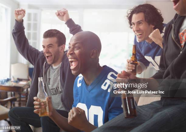 men drinking beer and cheering at game on television - beer bottle mouth stock-fotos und bilder