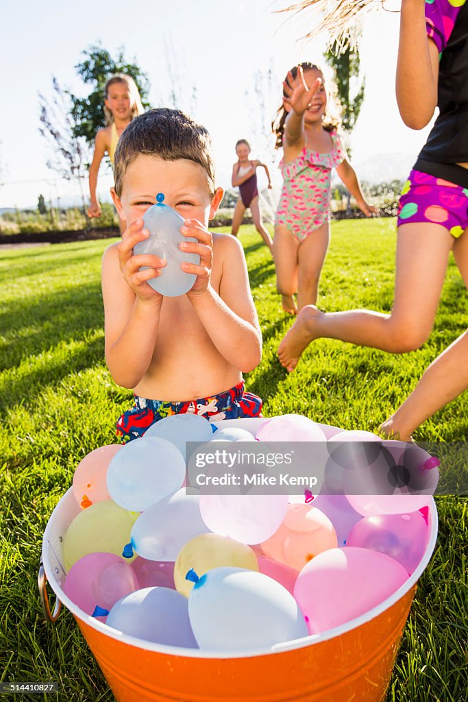 Caucasian children playing with water balloons in backyard