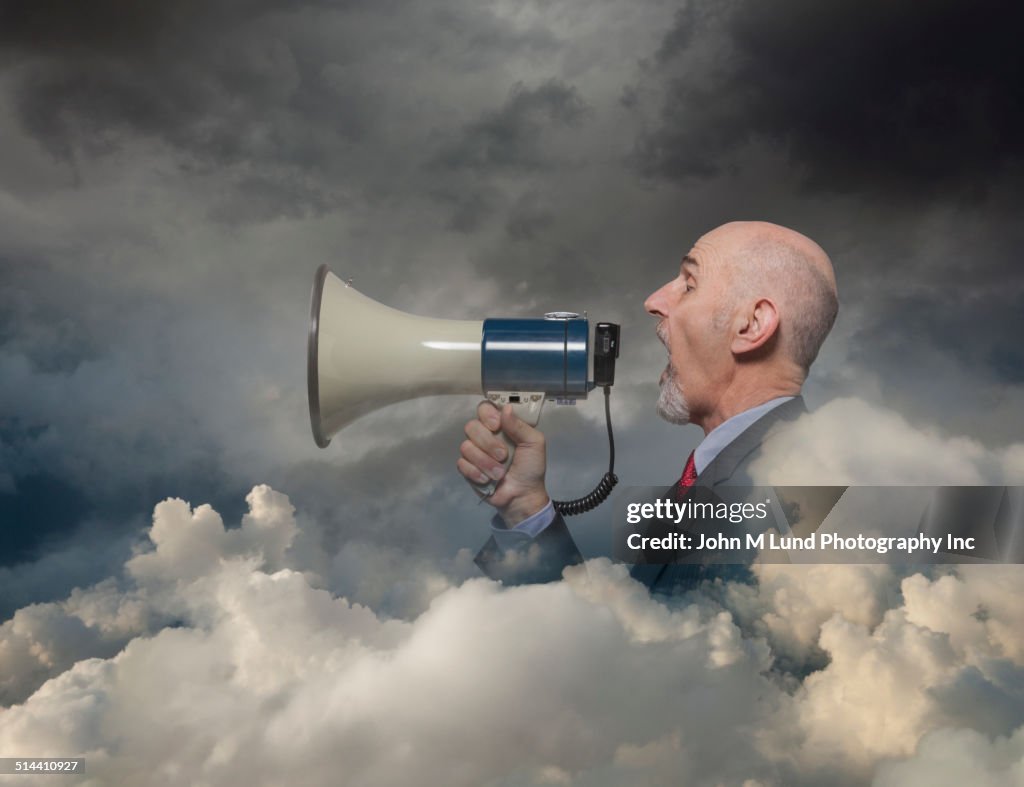 Caucasian businessman using megaphone in clouds