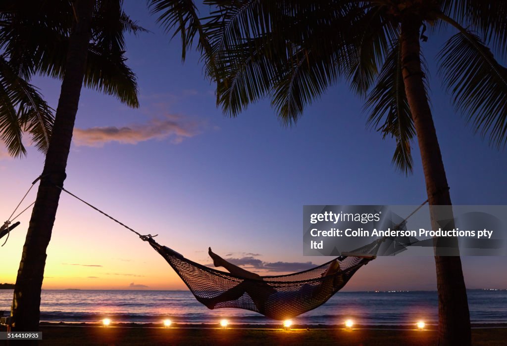 Silhouette of Caucasian woman relaxing in hammock at sunset