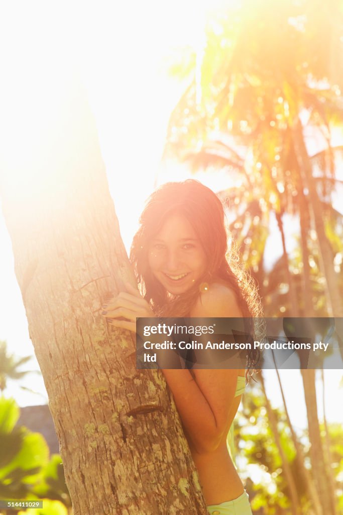 Caucasian girl hugging palm tree