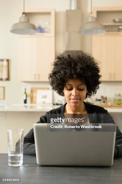 mixed race woman using laptop at breakfast table - roberto ricciuti foto e immagini stock