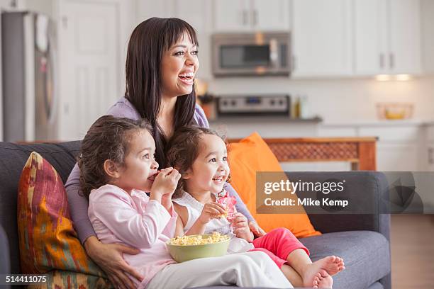 mother and daughters watching television on sofa - amour 2012 film stock pictures, royalty-free photos & images