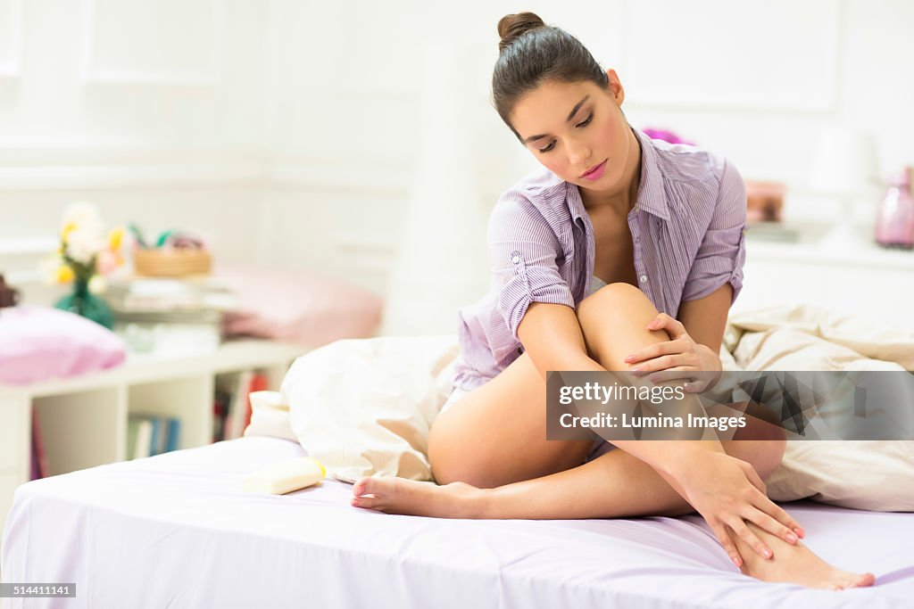 Caucasian woman applying moisturizer to leg