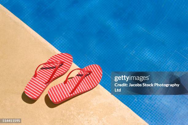 close up of flip flops by swimming pool - red shoe stock-fotos und bilder