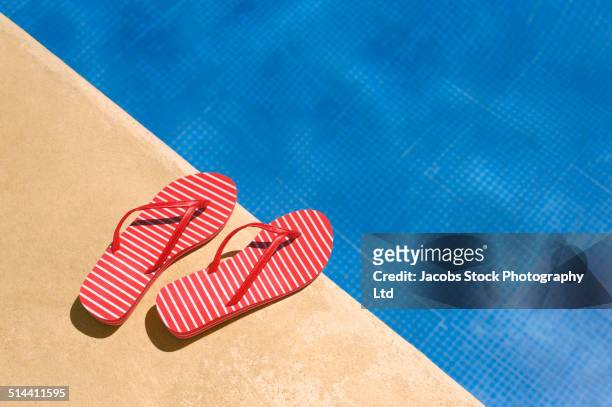 close up of flip flops by swimming pool - sandales photos et images de collection