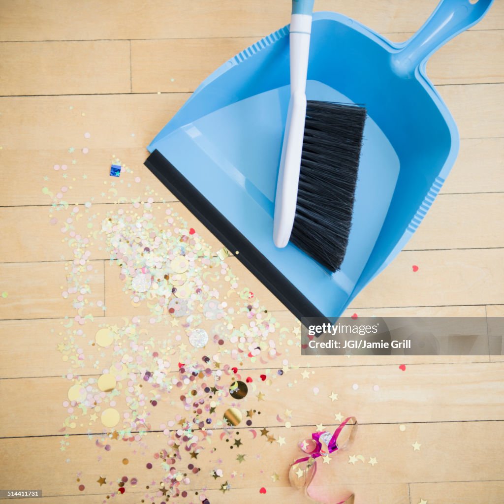 Broom and dustpan with confetti on floor