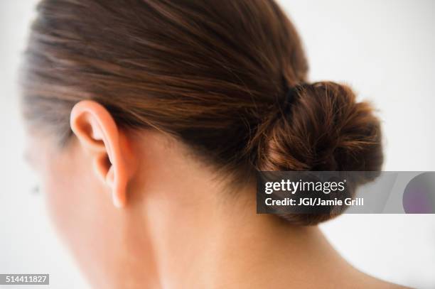 close up of woman wearing bun in hair - chignon foto e immagini stock