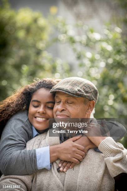 african american woman hugging father outdoors - sanft stock-fotos und bilder