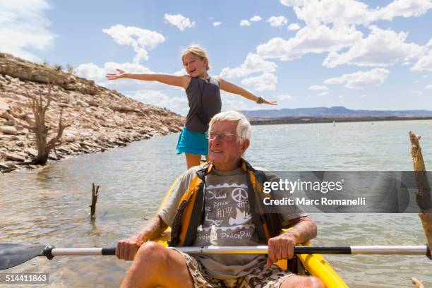 older caucasian man rowing kayak with granddaughter - seniors canoeing stock pictures, royalty-free photos & images