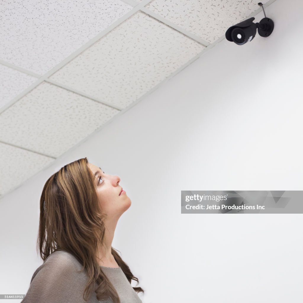 Mixed race businesswoman looking at security camera in office