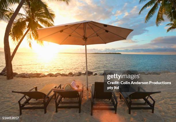 caucasian woman laying in deck chair on tropical beach - couché de soleil photos et images de collection