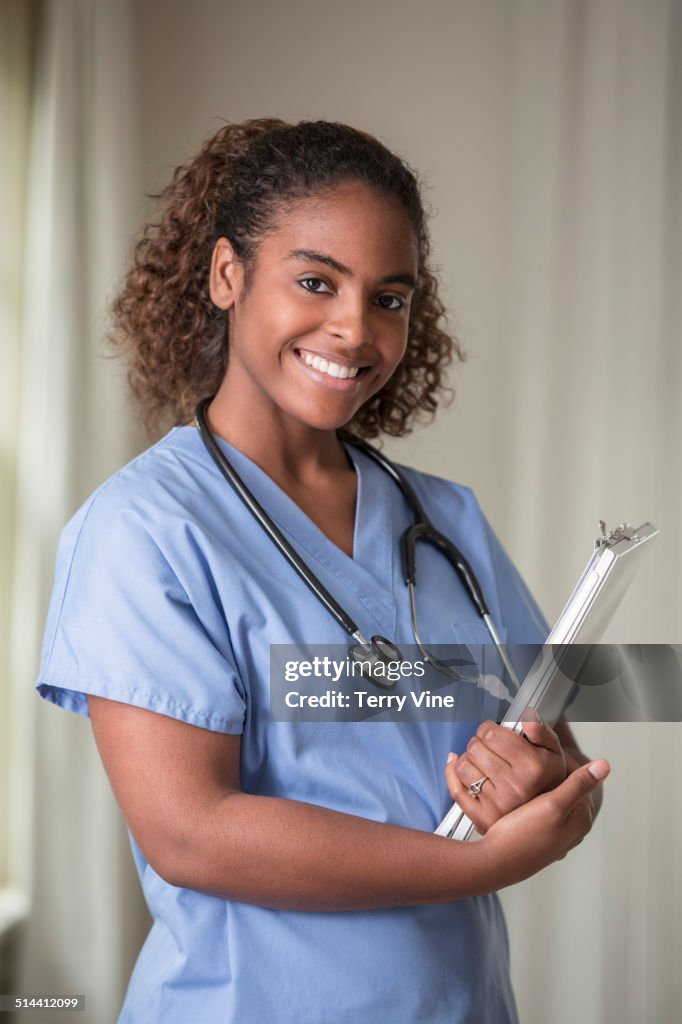 African American nurse holding medical chart in hospital