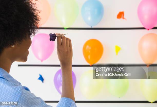 african american woman popping balloons with dart - fair game foto e immagini stock