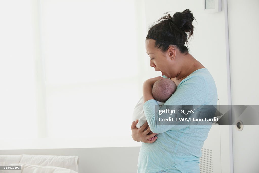 Yawning Chinese mother holding newborn