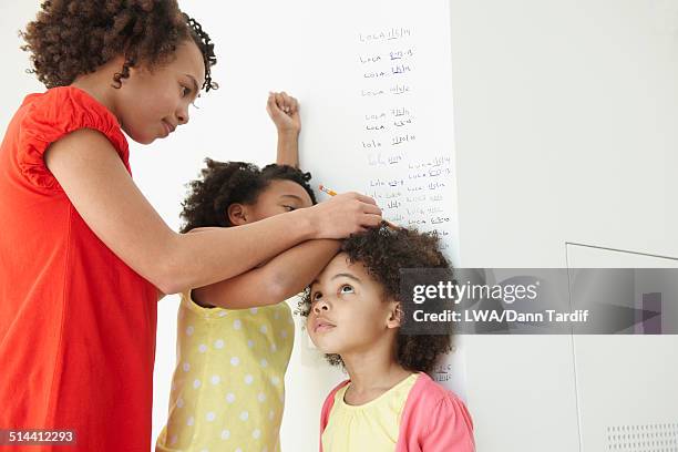 black girls measuring their height on wall - child's wall height stock-fotos und bilder