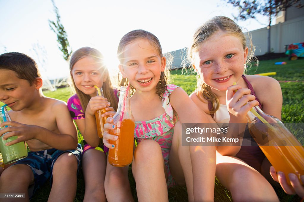 Caucasian children drinking soda in backyard