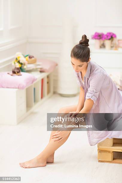 caucasian woman applying moisturizer to leg - woman leg spread stock pictures, royalty-free photos & images