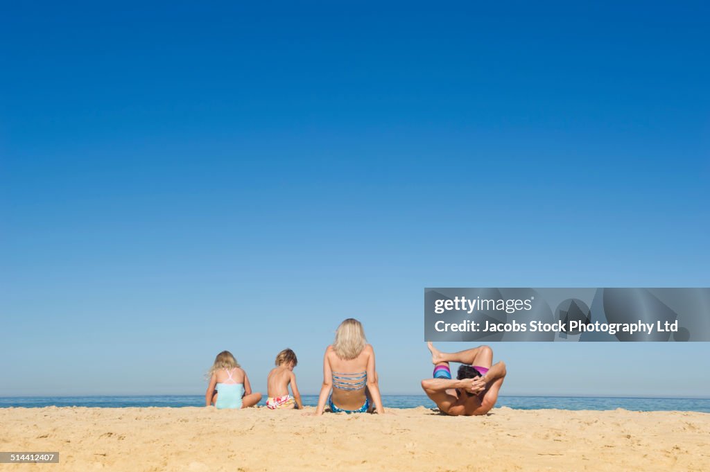 Caucasian family relaxing together on beach