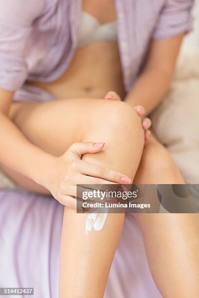 caucasian woman applying moisturizer to leg - woman leg spread stock pictures, royalty-free photos & images