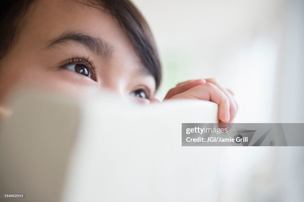 Close up of Filipino girl peering over chair back