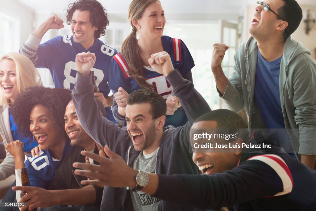 Friends cheering at game on television