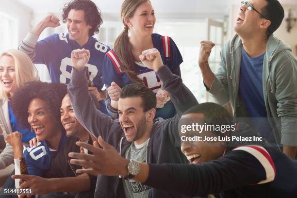 friends cheering at game on television - woman in sports jersey stock pictures, royalty-free photos & images