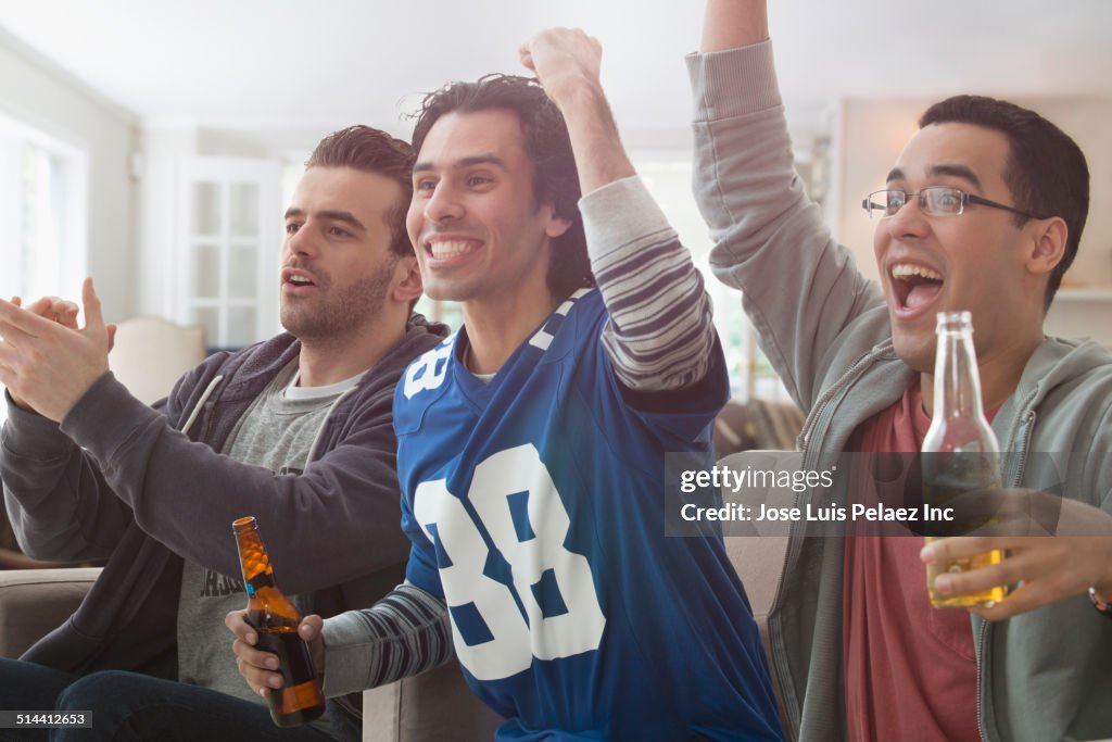 Men drinking beer and cheering at game on television